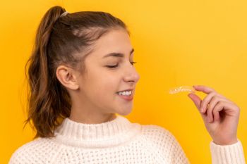 woman smiling holding invisalign aligners